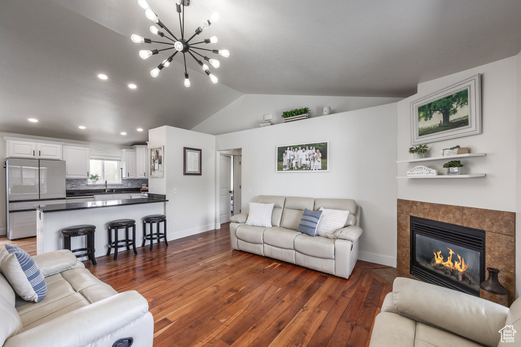 Living room with baseboards, hardwood / wood-style floors, a chandelier, vaulted ceiling, and recessed lighting