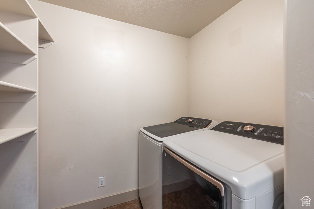 Washroom with washing machine and clothes dryer and a textured ceiling