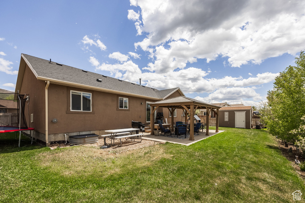 Back of property featuring a trampoline, a gazebo, a patio area, and a yard