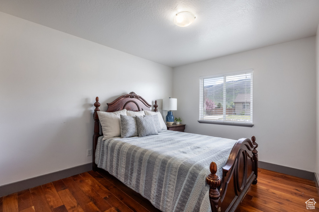 Bedroom with baseboards and dark wood-type flooring