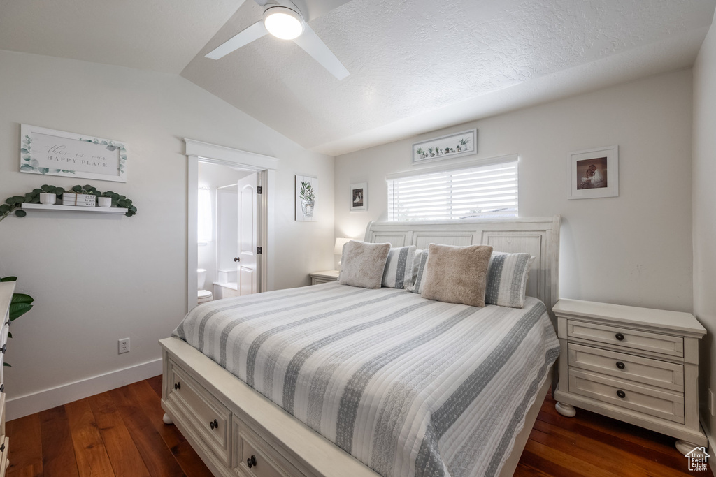 Bedroom featuring lofted ceiling, dark wood-type flooring, ensuite bathroom, baseboards, and ceiling fan