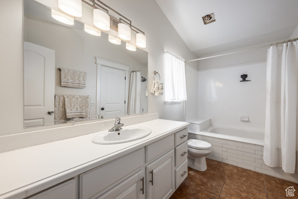 Full bathroom featuring lofted ceiling, toilet, vanity, shower / bath combo, and tile patterned flooring