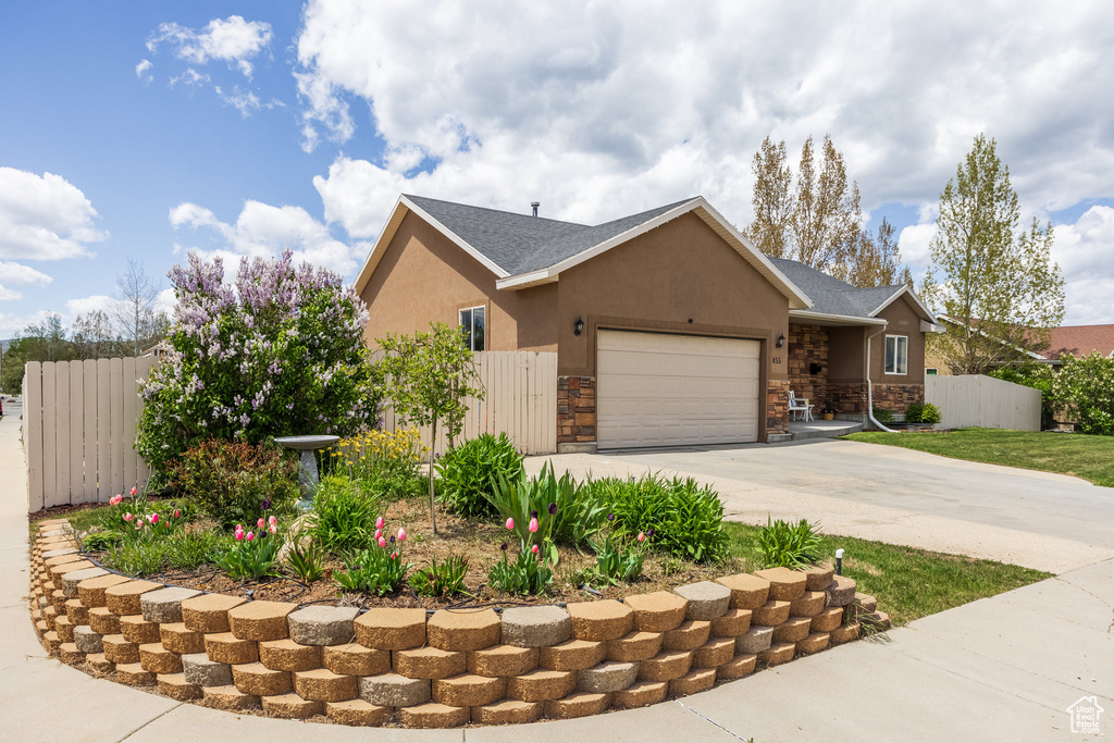 View of front of house with an attached garage, concrete driveway, stone siding, stucco siding, and a shingled roof
