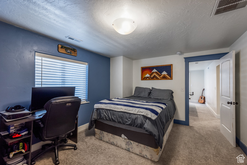 Carpeted bedroom with a textured ceiling, baseboards, and an office area