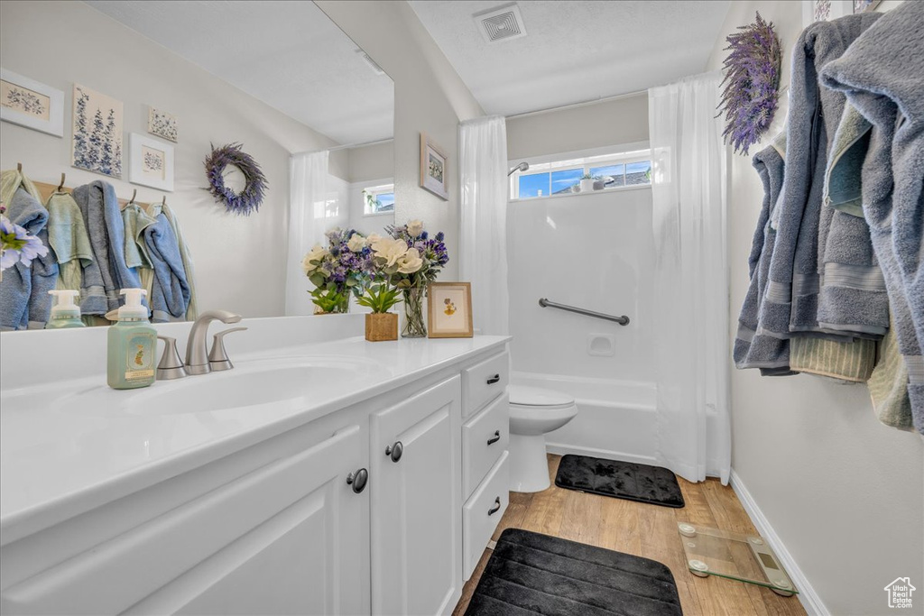 Full bathroom featuring vanity, wood finished floors, toilet, shower / bath combination with curtain, and baseboards