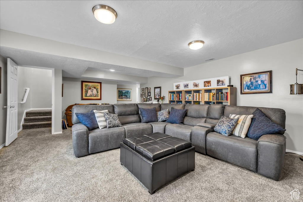 Carpeted living area featuring baseboards, a textured ceiling, and stairway
