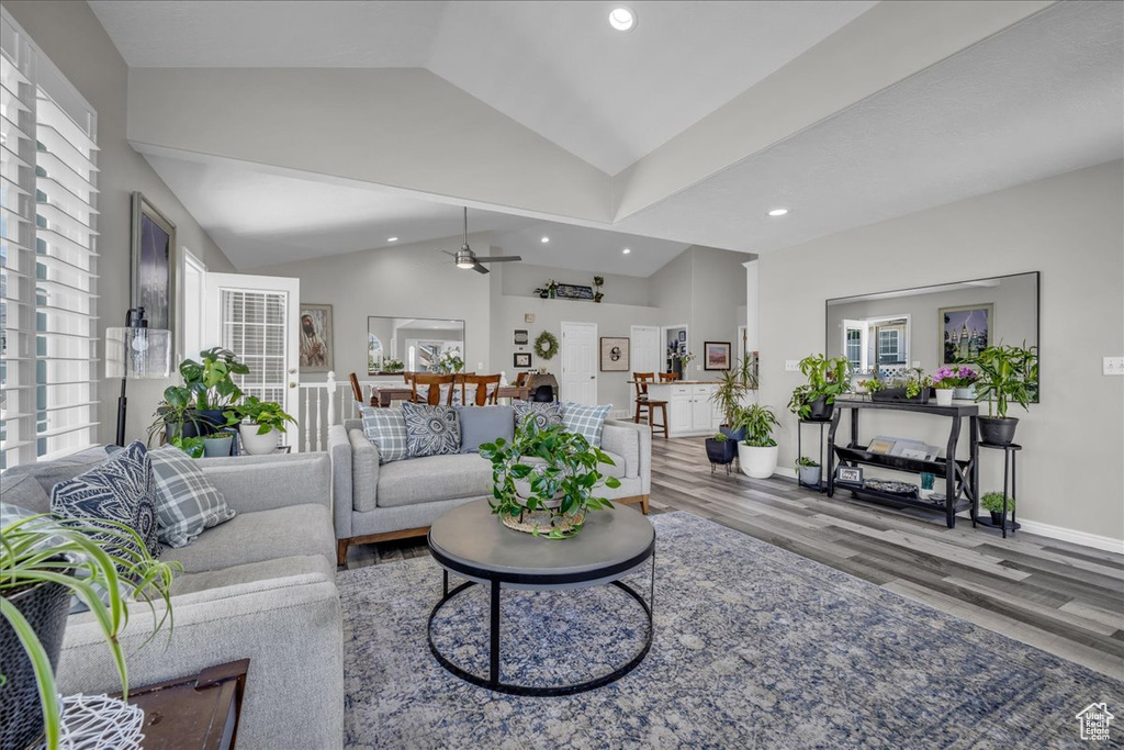 Living area with lofted ceiling, wood finished floors, plenty of natural light, recessed lighting, and baseboards