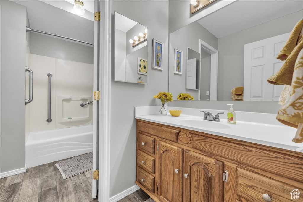 Full bathroom featuring wood finished floors, vanity, and baseboards