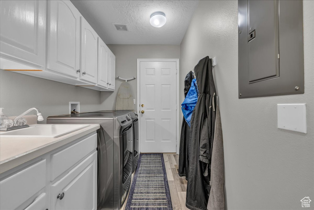Laundry area with washing machine and clothes dryer, electric panel, cabinet space, and a textured ceiling