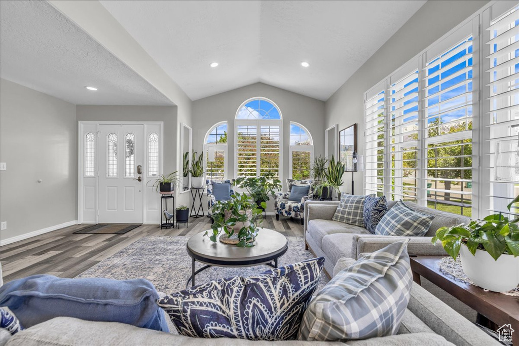 Living area with wood finished floors, baseboards, vaulted ceiling, and recessed lighting