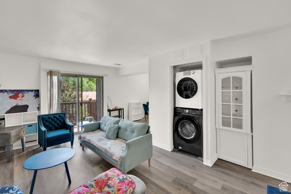 Living area featuring stacked washing machine and dryer, wood finished floors, and baseboards
