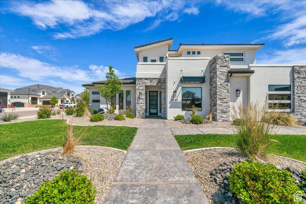 Modern home with stucco siding, stone siding, a front yard, and a residential view