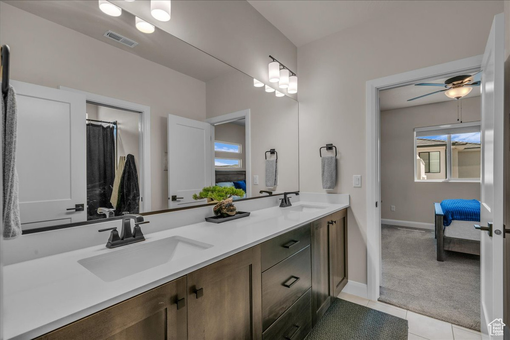 Full bath featuring double vanity, baseboards, ensuite bath, tile patterned flooring, and a ceiling fan