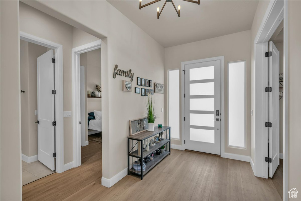Foyer entrance with wood finished floors, a chandelier, and baseboards