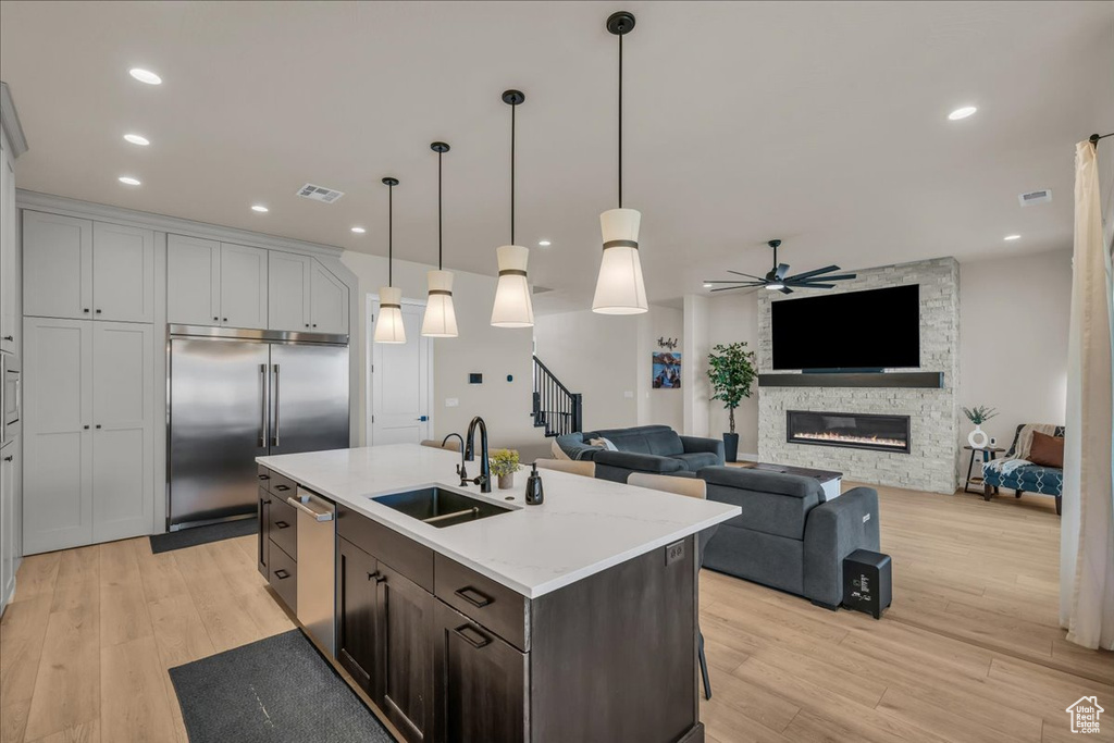 Kitchen with a sink, stainless steel appliances, light wood finished floors, ceiling fan, and pendant lighting