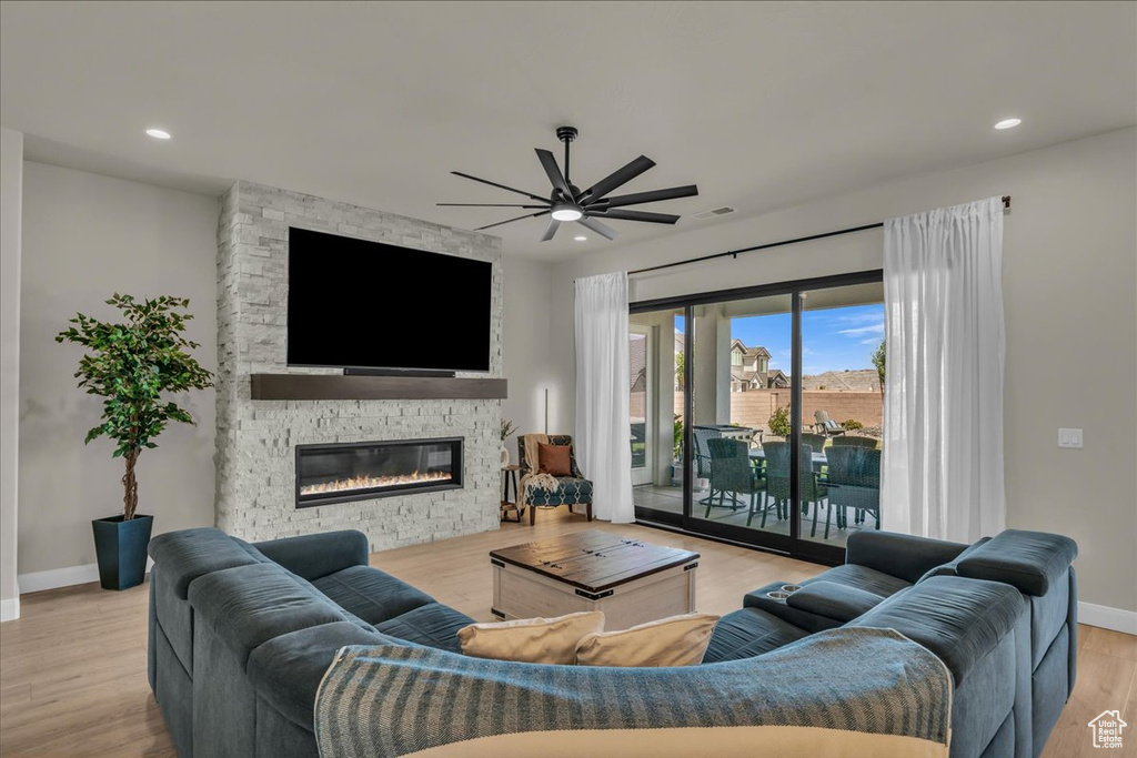 Living room with a ceiling fan, baseboards, a stone fireplace, wood finished floors, and recessed lighting