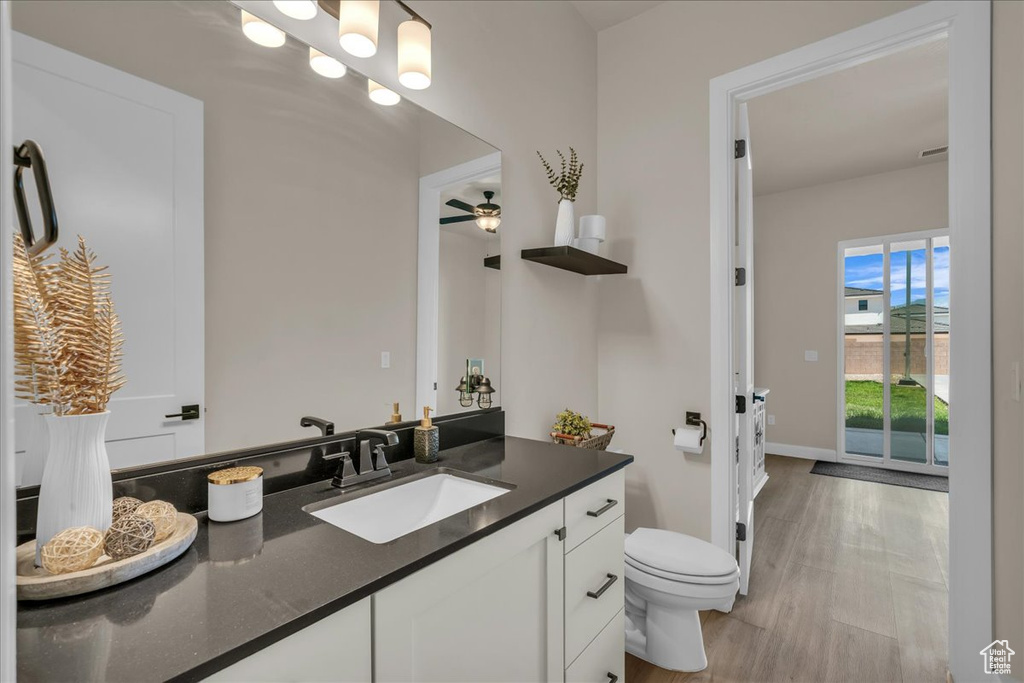 Bathroom with vanity, toilet, wood finished floors, and baseboards
