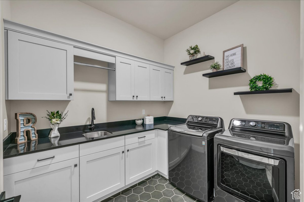 Washroom with washing machine and clothes dryer, cabinet space, and dark tile patterned flooring