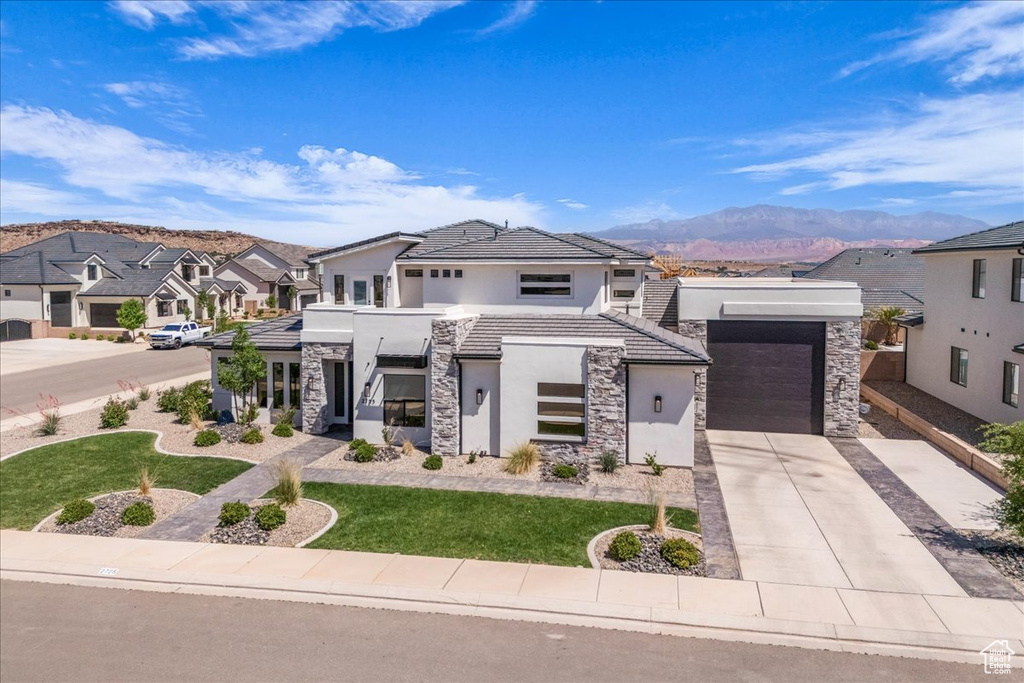 Contemporary home with stone siding, stucco siding, concrete driveway, and a mountain view