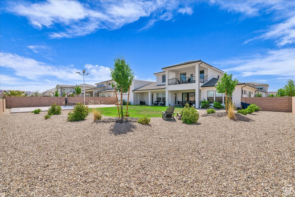 Rear view of property featuring a balcony, stucco siding, and a patio area