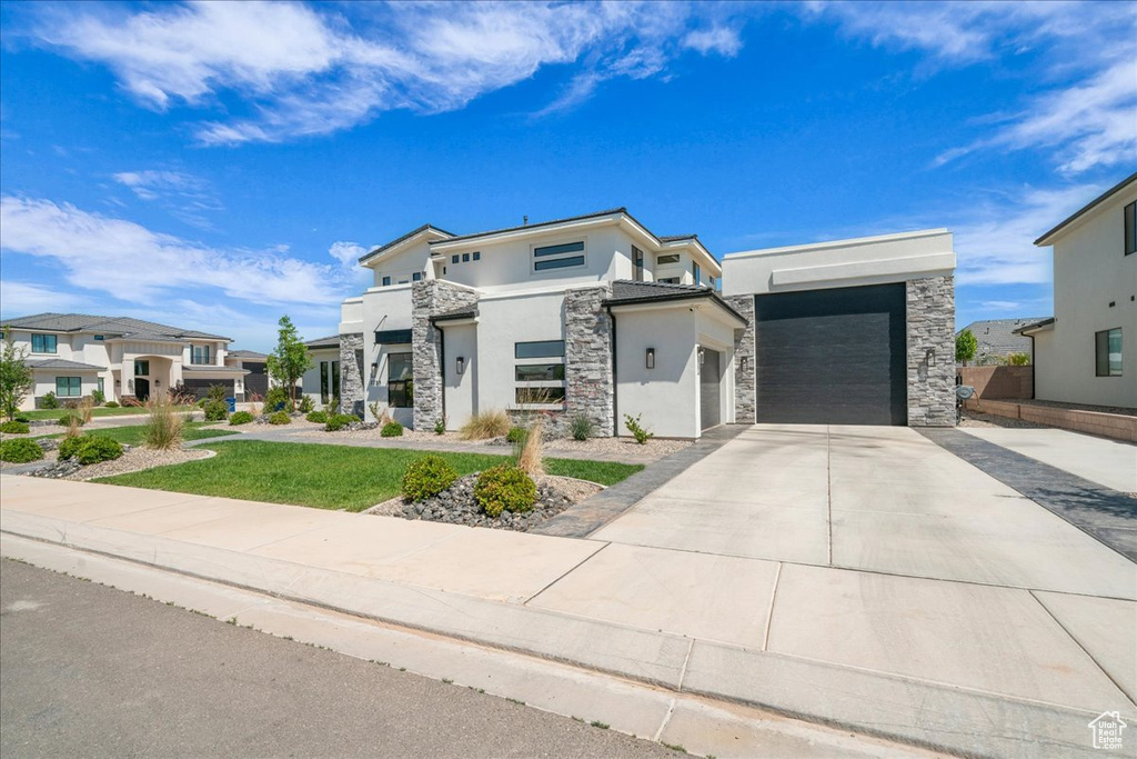 Contemporary home with stucco siding, stone siding, driveway, a residential view, and a garage