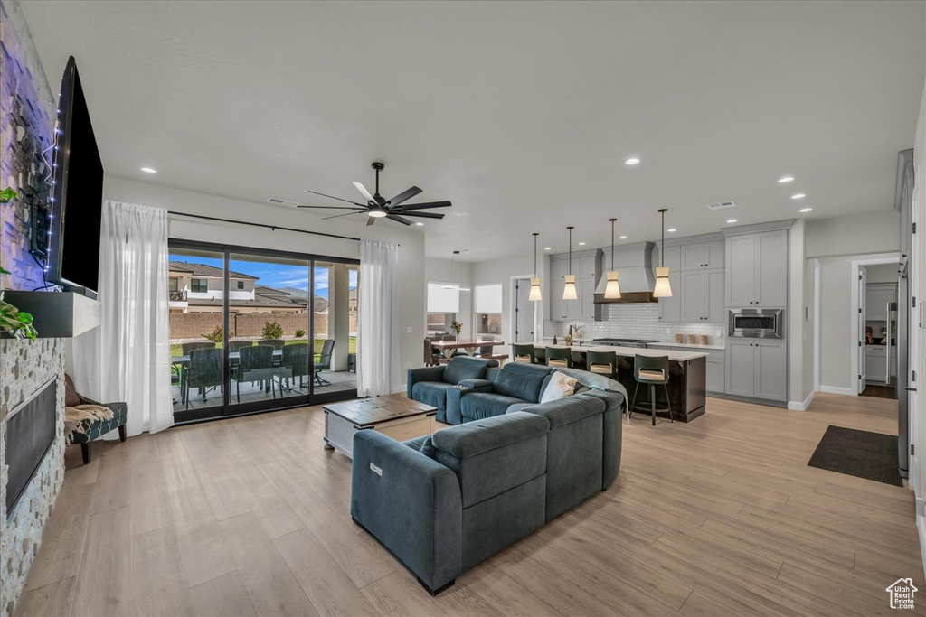 Living room with a ceiling fan, light wood-style floors, a fireplace, and recessed lighting