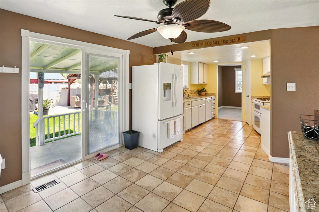 Kitchen with white appliances, a sink, a ceiling fan, light countertops, and under cabinet range hood