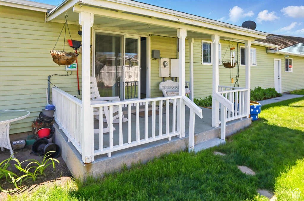 View of exterior entry featuring a porch and a lawn