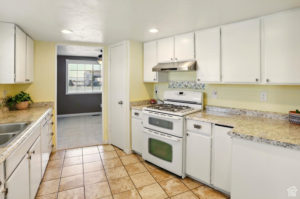 Kitchen with double oven range, under cabinet range hood, white cabinetry, and recessed lighting