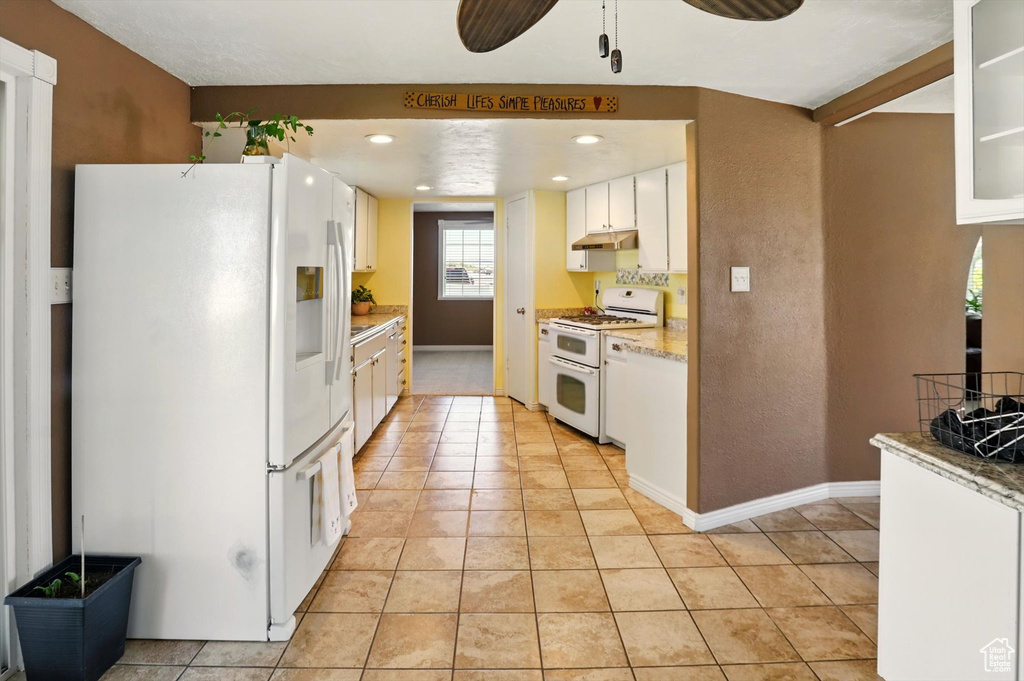 Kitchen with white appliances, under cabinet range hood, light tile patterned floors, white cabinetry, and recessed lighting