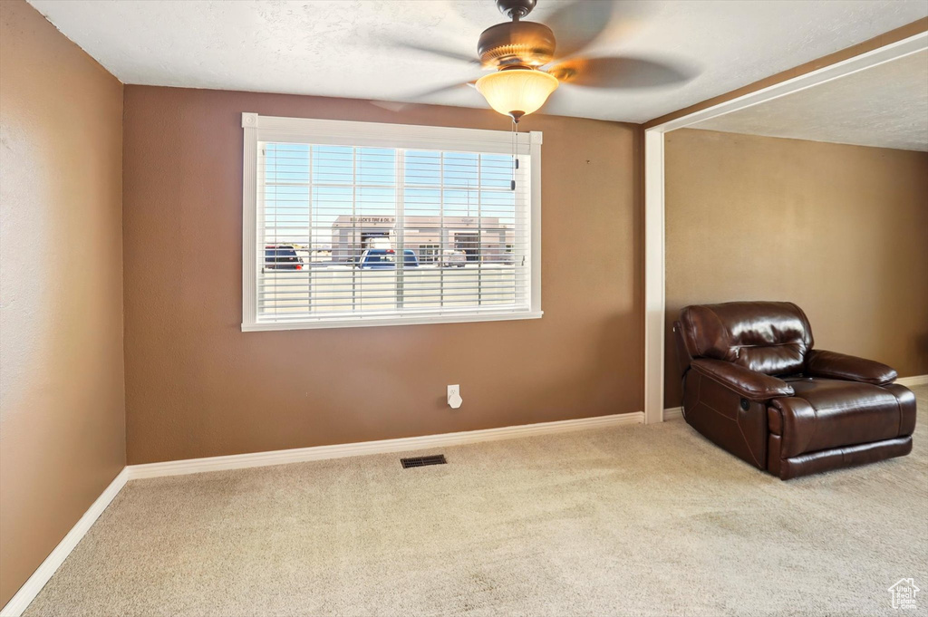 Living area with a ceiling fan, carpet floors, and baseboards