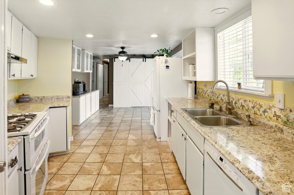 Kitchen with white appliances, a sink, under cabinet range hood, white cabinetry, and recessed lighting