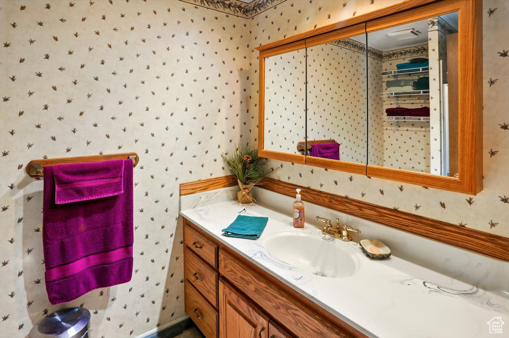 Bathroom with wallpapered walls and vanity