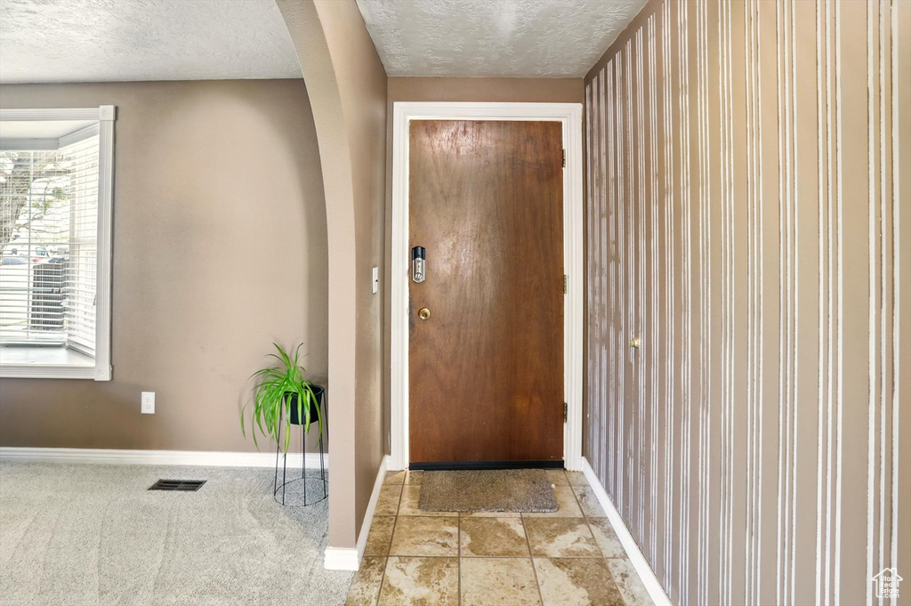 Doorway to outside with baseboards, a textured ceiling, and arched walkways