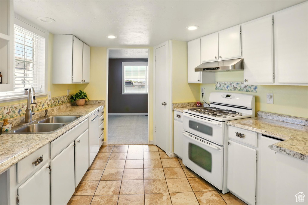 Kitchen with double oven range, a sink, under cabinet range hood, white cabinets, and recessed lighting