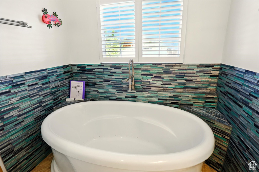 Full bathroom featuring tile walls, a freestanding bath, and wainscoting