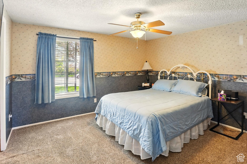 Bedroom with wallpapered walls, a textured ceiling, carpet floors, and a ceiling fan