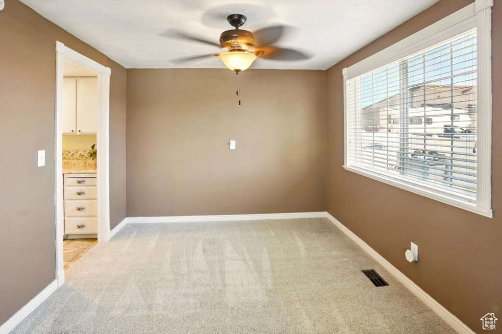 Spare room featuring a ceiling fan, light carpet, and baseboards