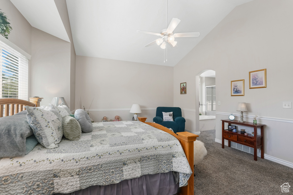 Carpeted bedroom featuring arched walkways, high vaulted ceiling, baseboards, ensuite bath, and ceiling fan