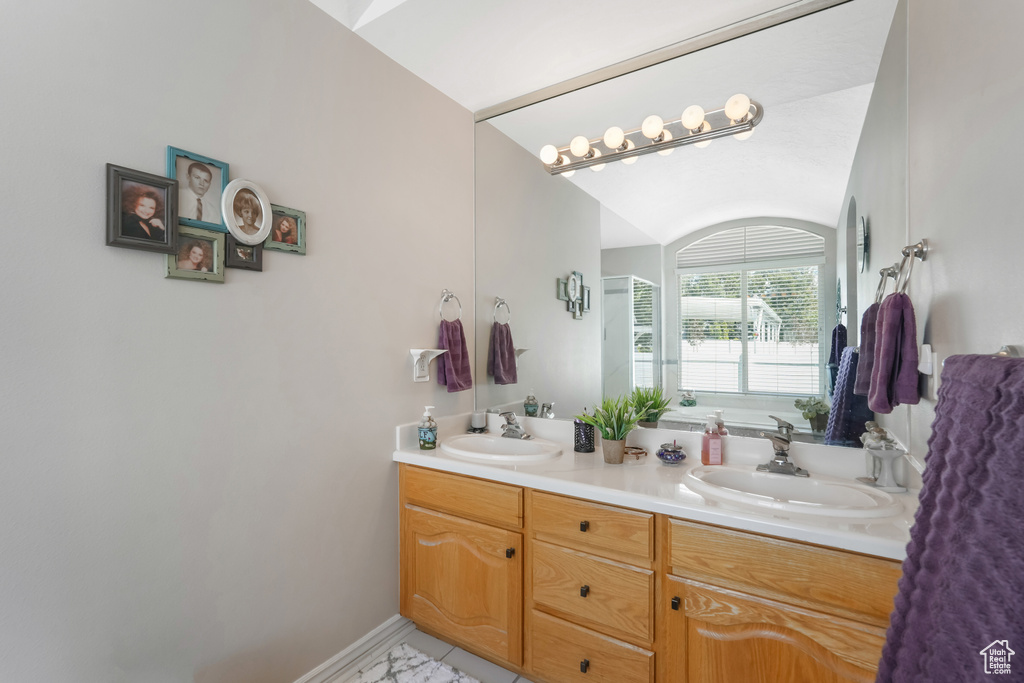 Bathroom with double vanity, lofted ceiling, and baseboards