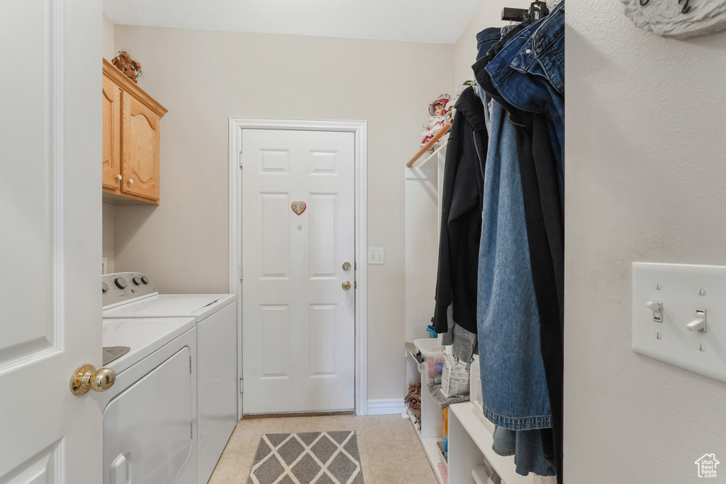 Laundry room with washing machine and clothes dryer, cabinet space, and light tile patterned flooring