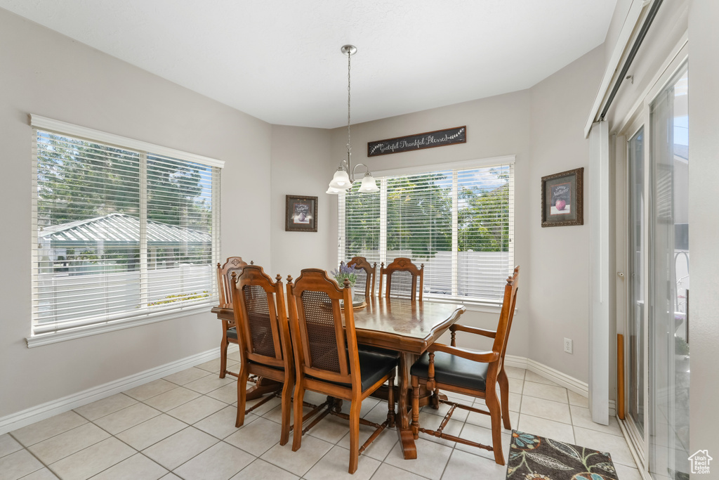 Dining space with plenty of natural light, a chandelier, light tile patterned flooring, and baseboards