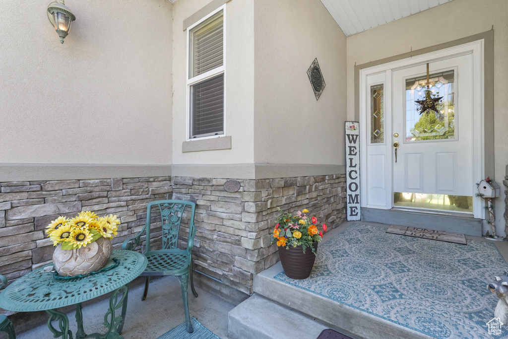 View of exterior entry with stucco siding, stone siding, and a porch