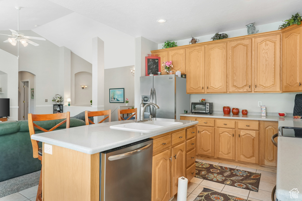 Kitchen with appliances with stainless steel finishes, a sink, light tile patterned flooring, ceiling fan, and light countertops