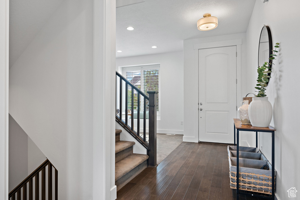Entrance foyer featuring dark wood finished floors, stairs, recessed lighting, and baseboards