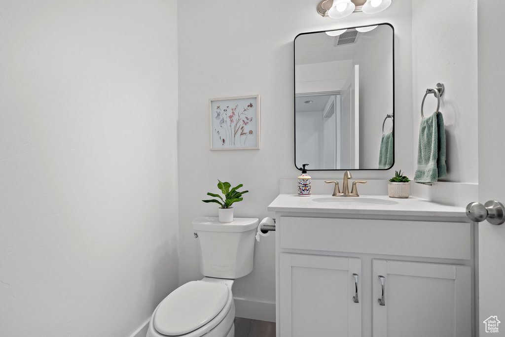 Bathroom featuring toilet, vanity, and baseboards