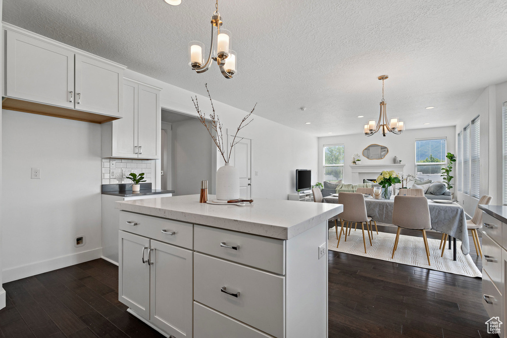 Kitchen featuring a chandelier, dark wood-style flooring, open floor plan, pendant lighting, and white cabinetry