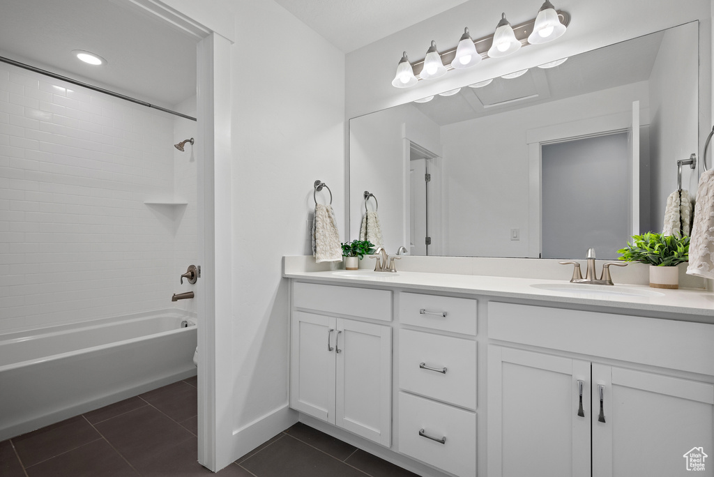 Full bath featuring tile patterned floors, double vanity, shower / bathtub combination, and baseboards
