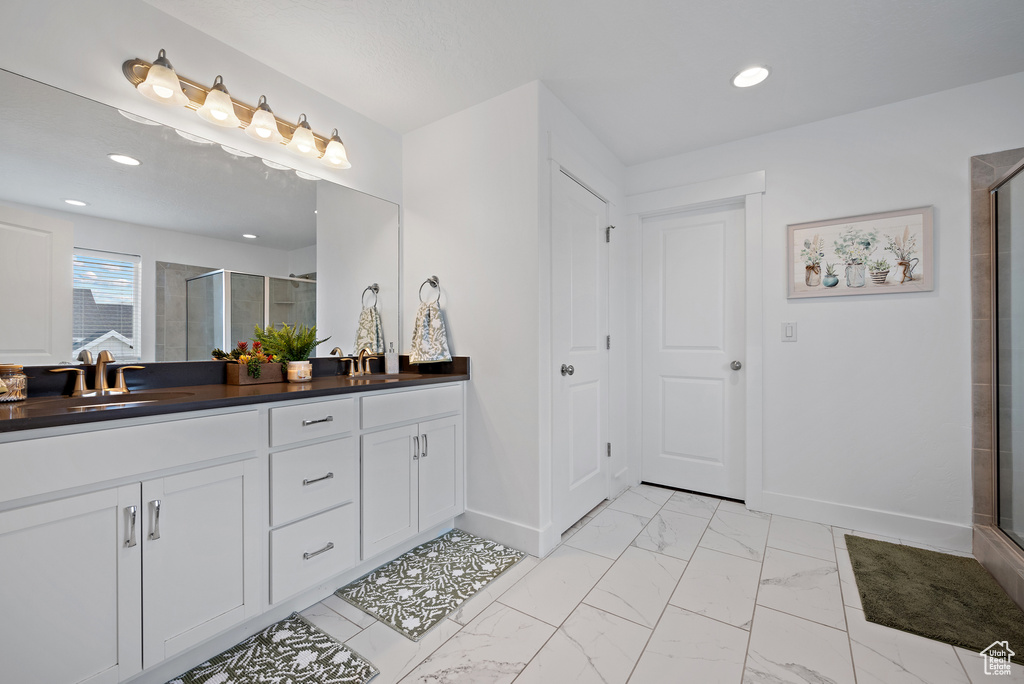 Bathroom with baseboards, double vanity, marble finish flooring, a shower stall, and recessed lighting