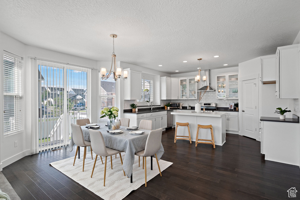 Dining room featuring a chandelier, a textured ceiling, dark wood-style floors, recessed lighting, and baseboards